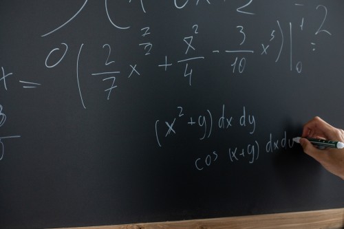 Math being written on a blackboard.